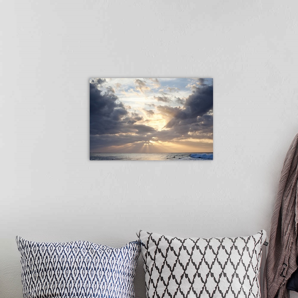 A bohemian room featuring Crepuscular rays of light break through the sky over the blue ocean, surfers in the background