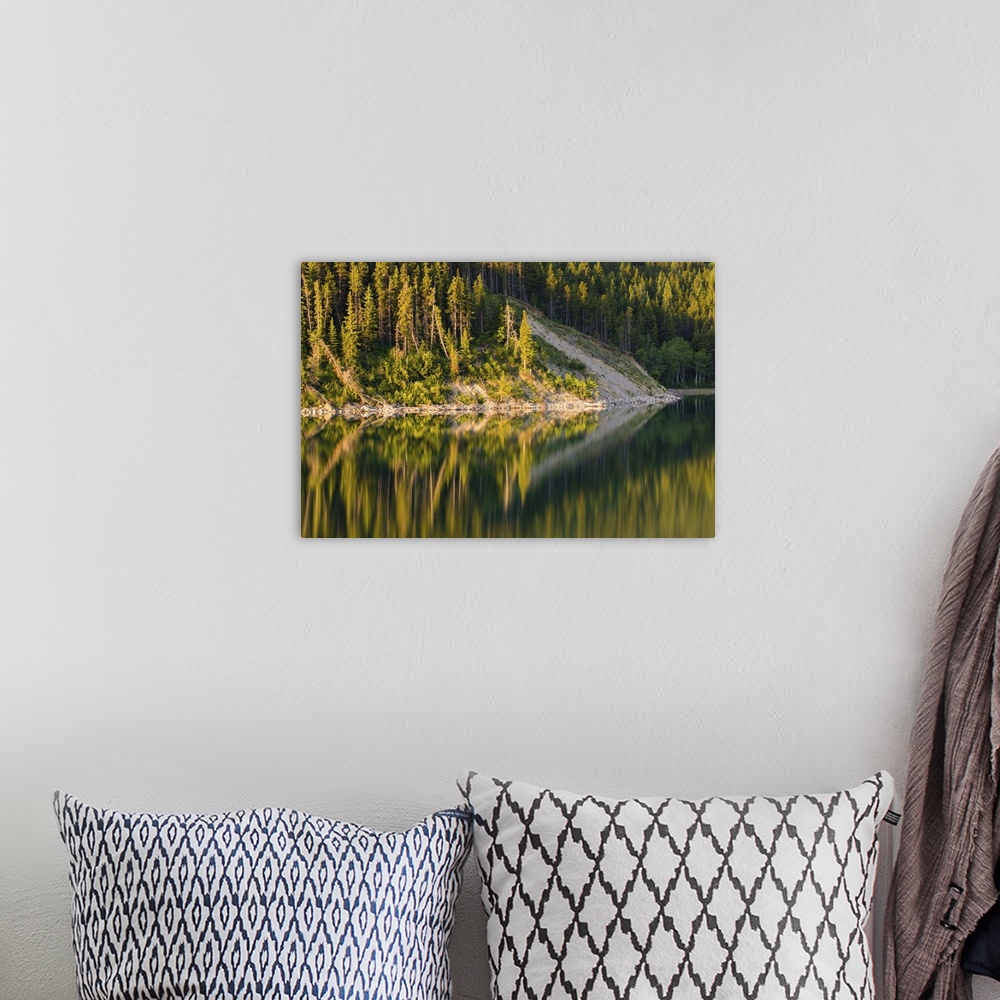 A bohemian room featuring Pine Trees reflect onto the still surface of Lake Sherburne in the Many Glacier Area of Glacier N...