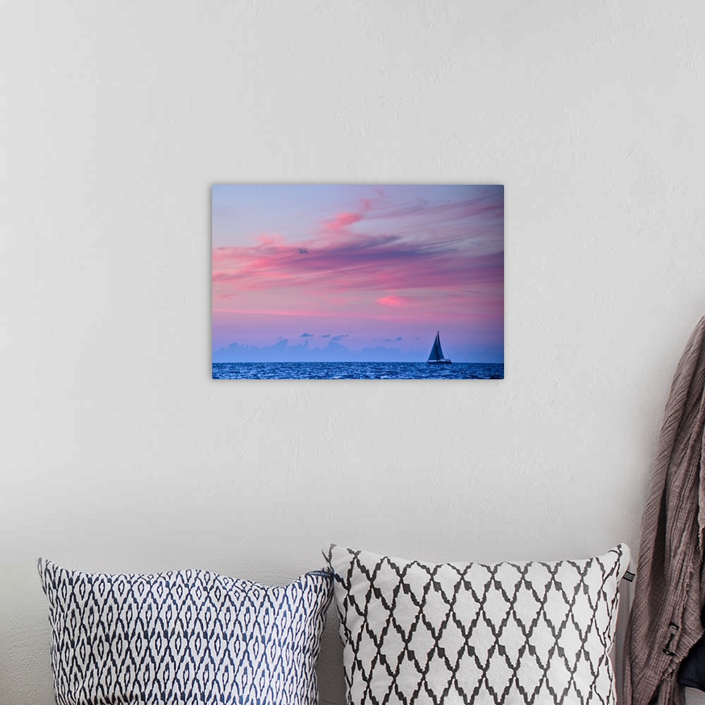 A bohemian room featuring Feathery clouds, colored red from the sunset, over a blue sea with a sail boat