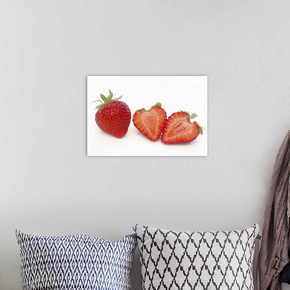 A bohemian room featuring Two fresh, ripe, home grown, organic strawberries, one cut into two halves, on a white background.