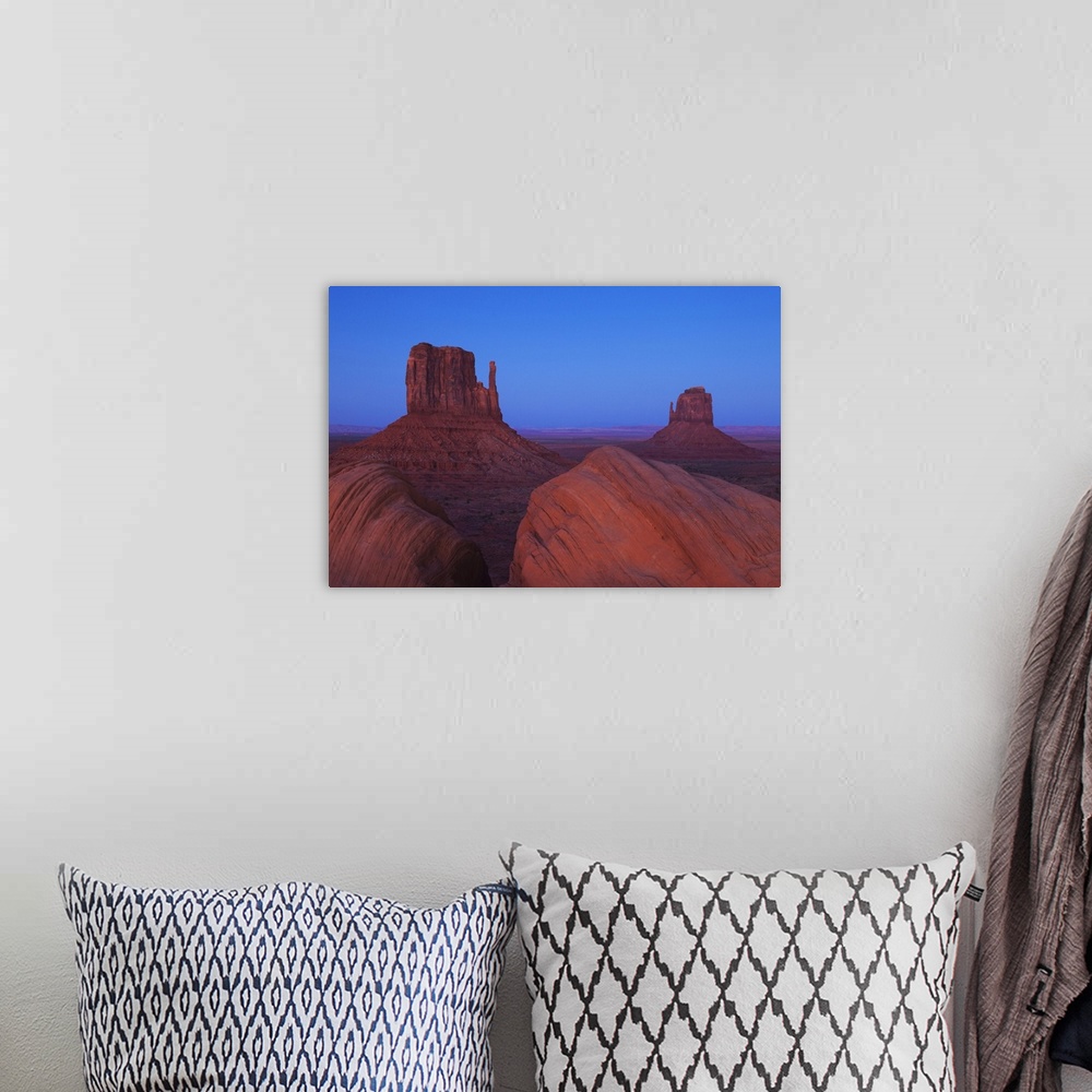A bohemian room featuring Monument Valley at dusk, with view of the West Mitten, the East Mitten and some foreground rock f...