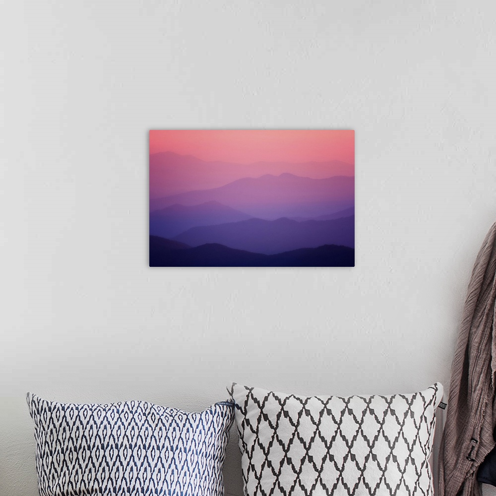A bohemian room featuring Layers of the smoky mountains reach into the distance as the sky turns pink and purple in the sun...