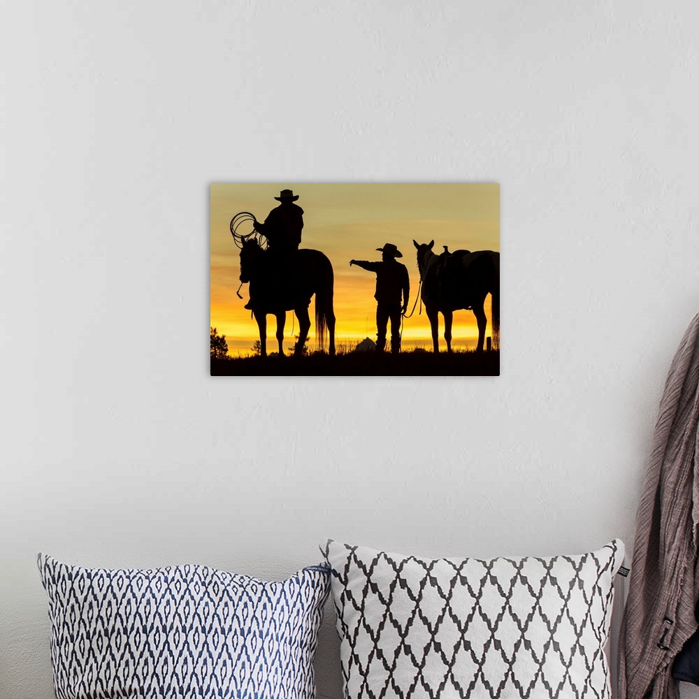 A bohemian room featuring Cowboys and horses in silhouette at dawn on ranch, British Colombia, Canada.