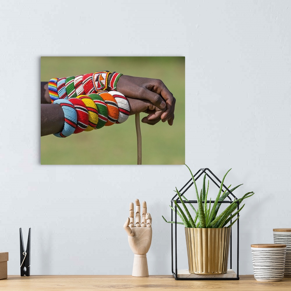 A bohemian room featuring Kenya, Samburu County, Bawa. A Samburu warrior with beaded bracelets rests his hands on a walking...