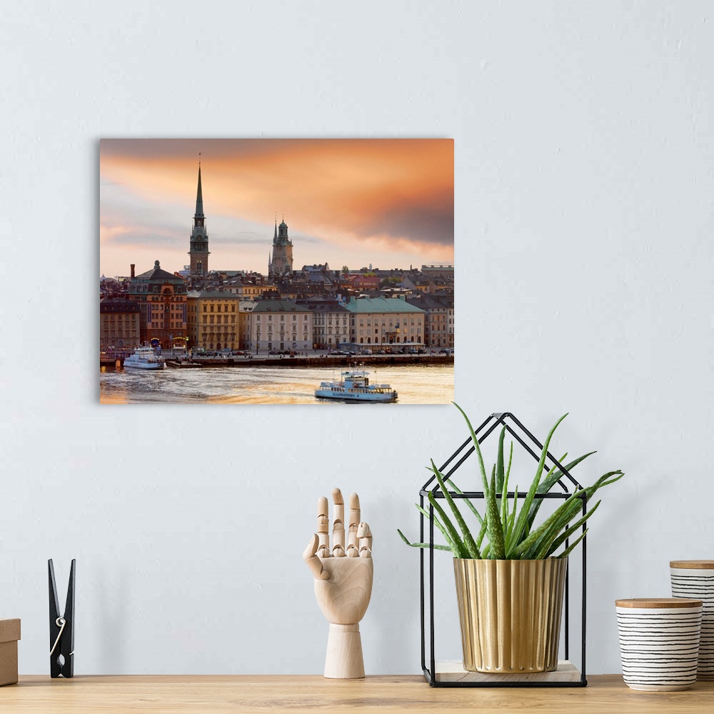 A bohemian room featuring Sweden, Stockholm, Riddarfjarden, Gamla Stan; passenger ferries in bay at dusk.