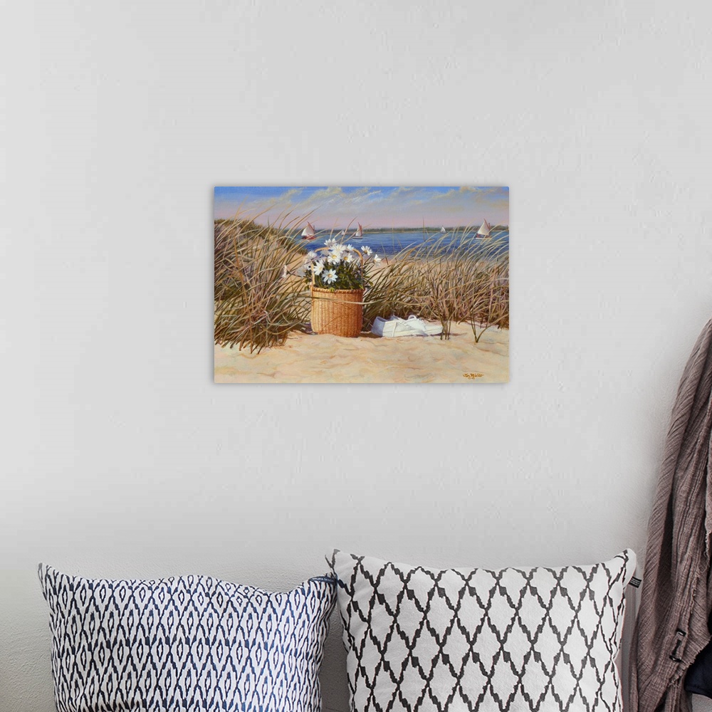A bohemian room featuring Basket of flowers with white sneakers in the sand and sea grass with sailboats in the water.