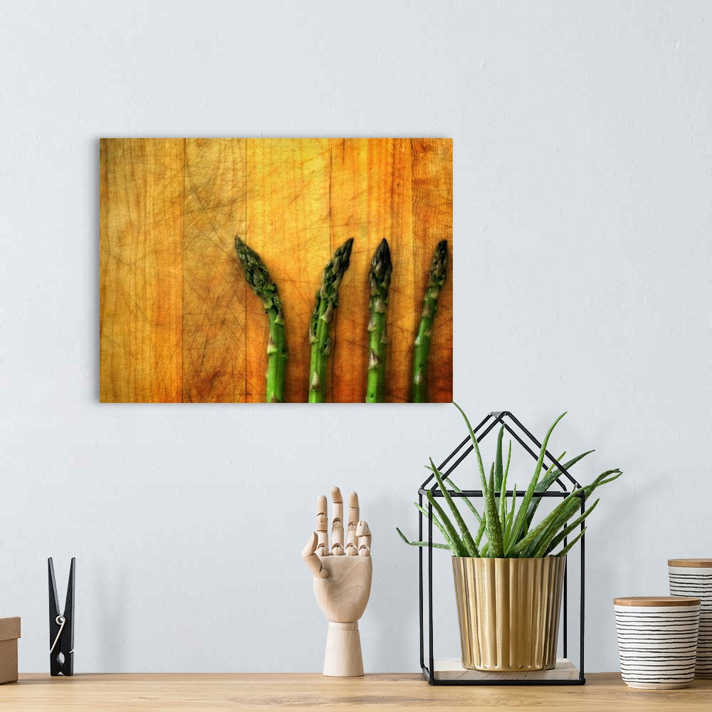 A bohemian room featuring Four green asparagus spears laying on a wooden surface.