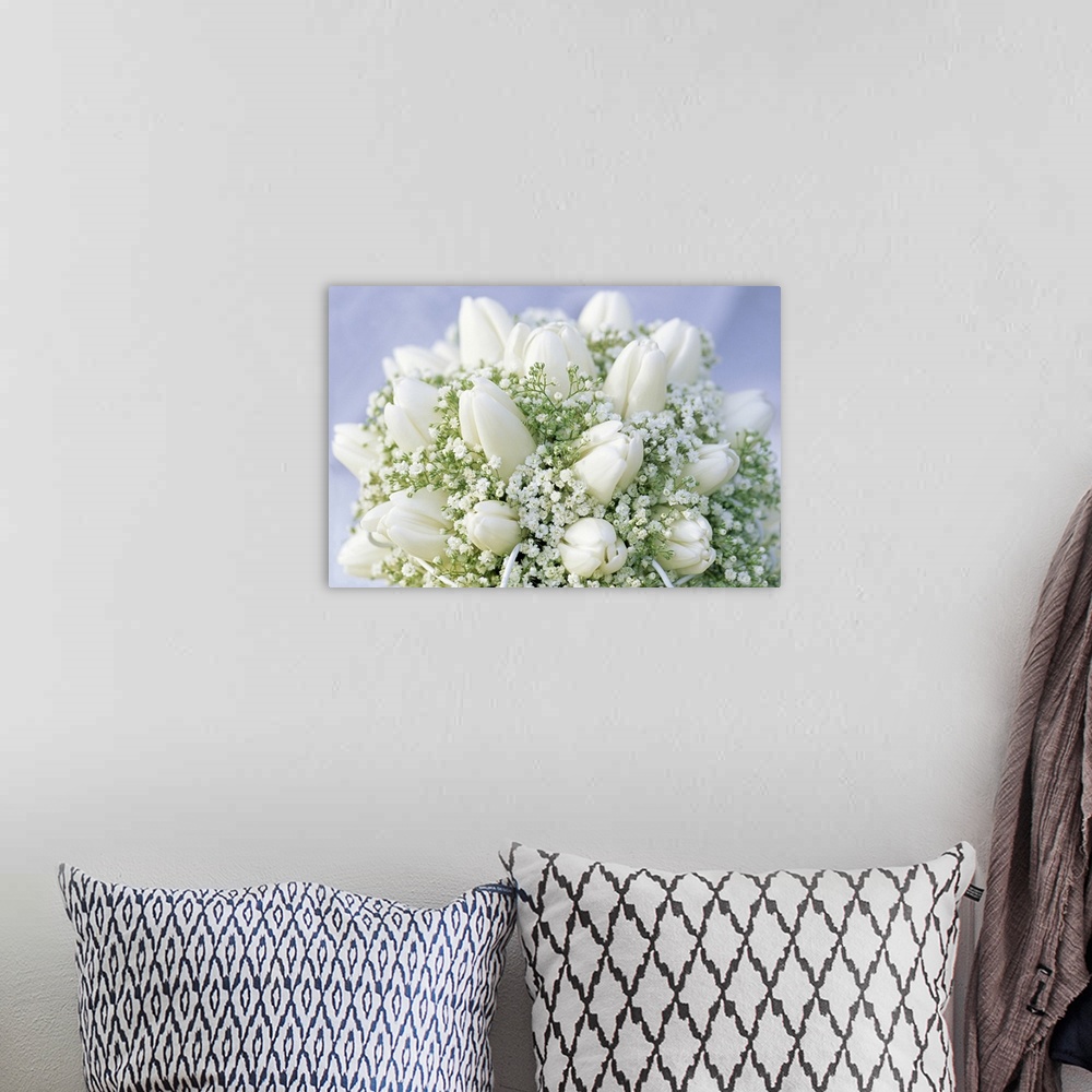 A bohemian room featuring Close up picture of a bouquet of closed white tulips and baby's' breath.