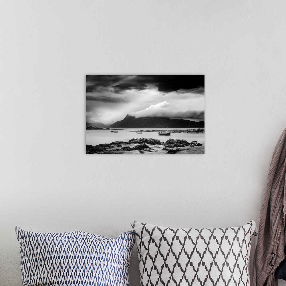 A bohemian room featuring Black and white landscape photograph of a cloudy sky over a mountainous lake with boats.