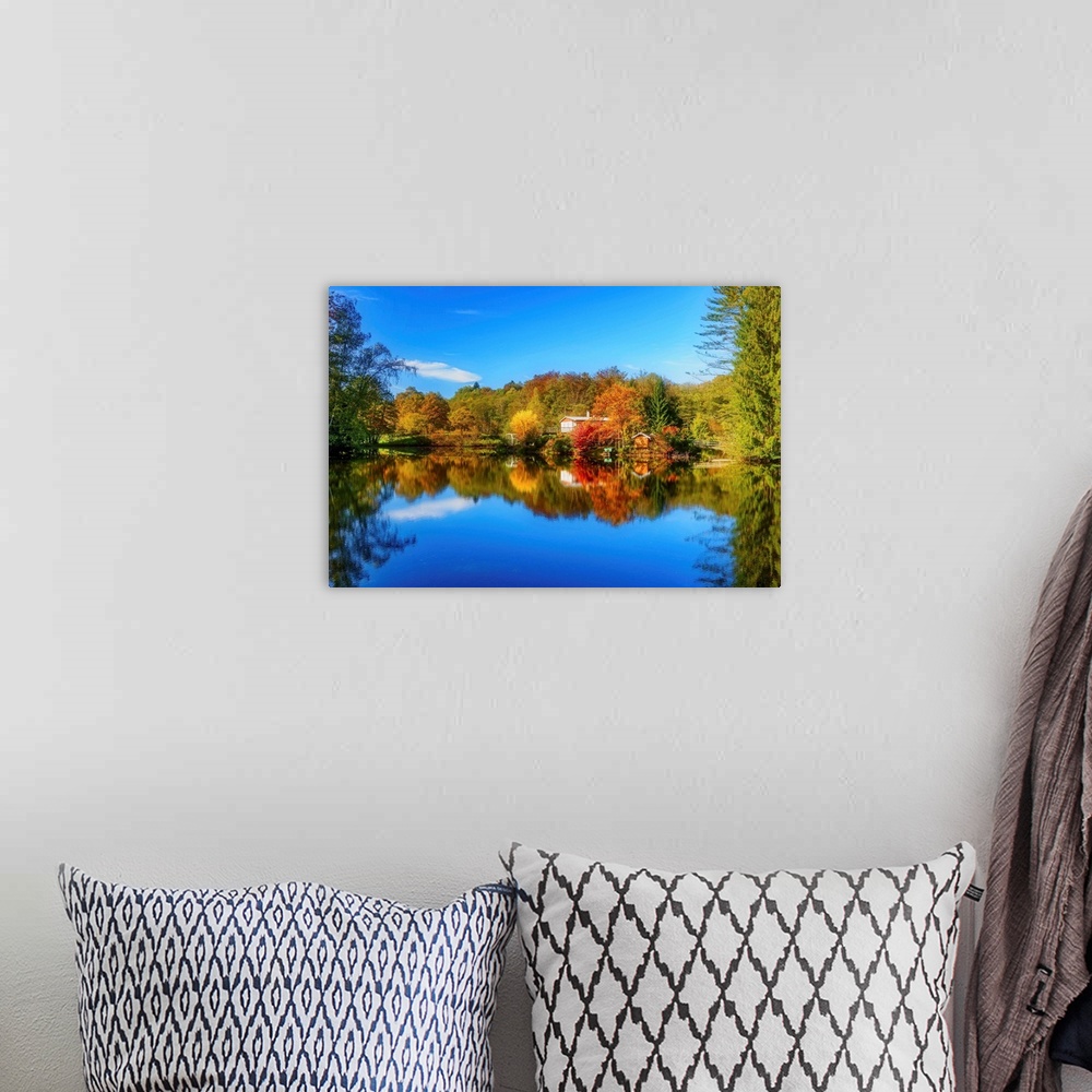 A bohemian room featuring Colorful trees in the fall and a deep blue sky reflected in the calm waters of a lake.