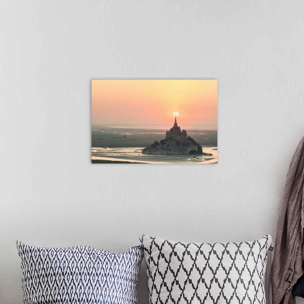 A bohemian room featuring The sun appearing to rest on the spire at the top of Mont Saint Michel in France at sunset.