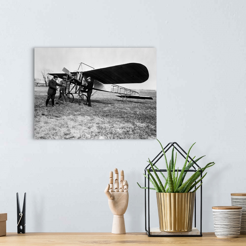 A bohemian room featuring 1910's Group Of Three Men Standing In Front Of Early Monoplane One With Hand On Propeller.