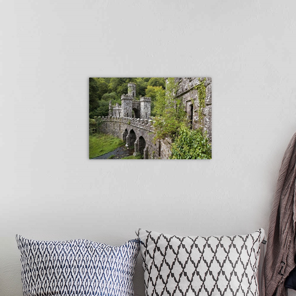 A bohemian room featuring A side angle view of a large stone bridge and towers that are surrounded by greenery in Ireland.