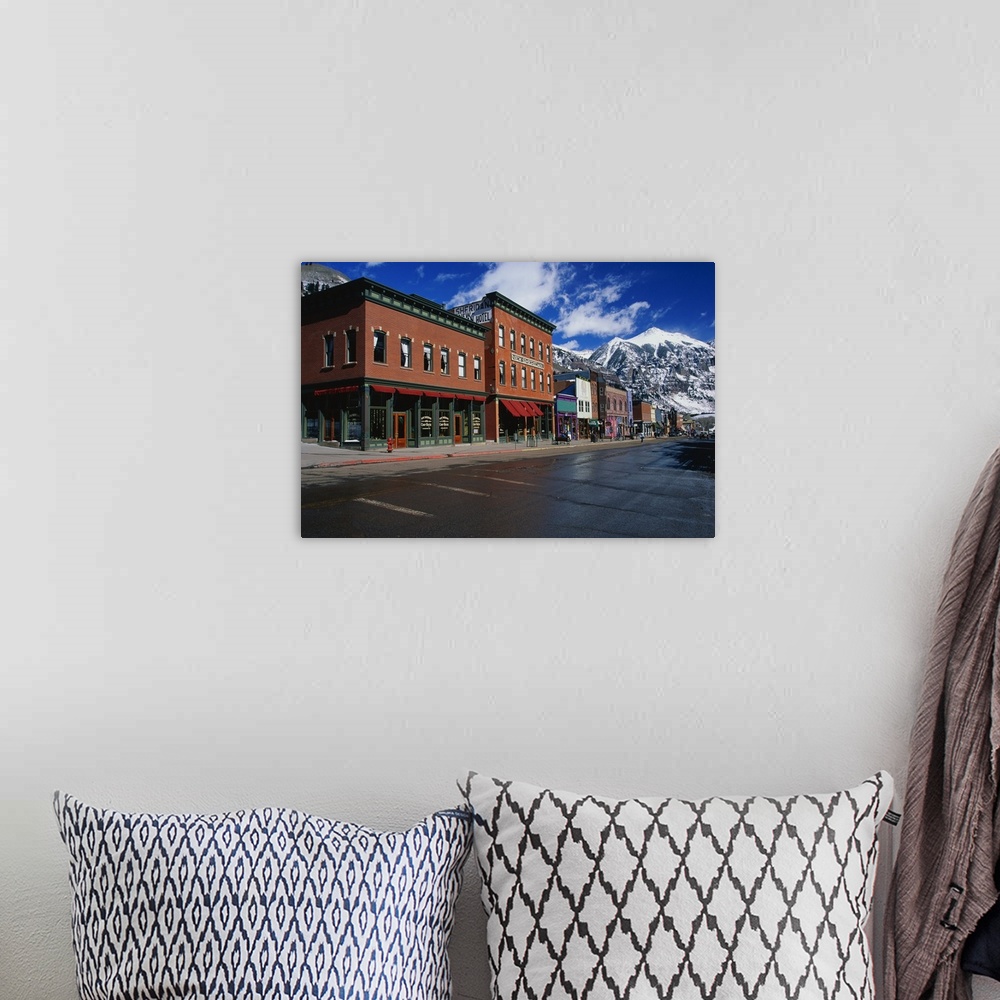 A bohemian room featuring Photograph of street corner lined with buildings and shops with snow covered mountains in the bac...