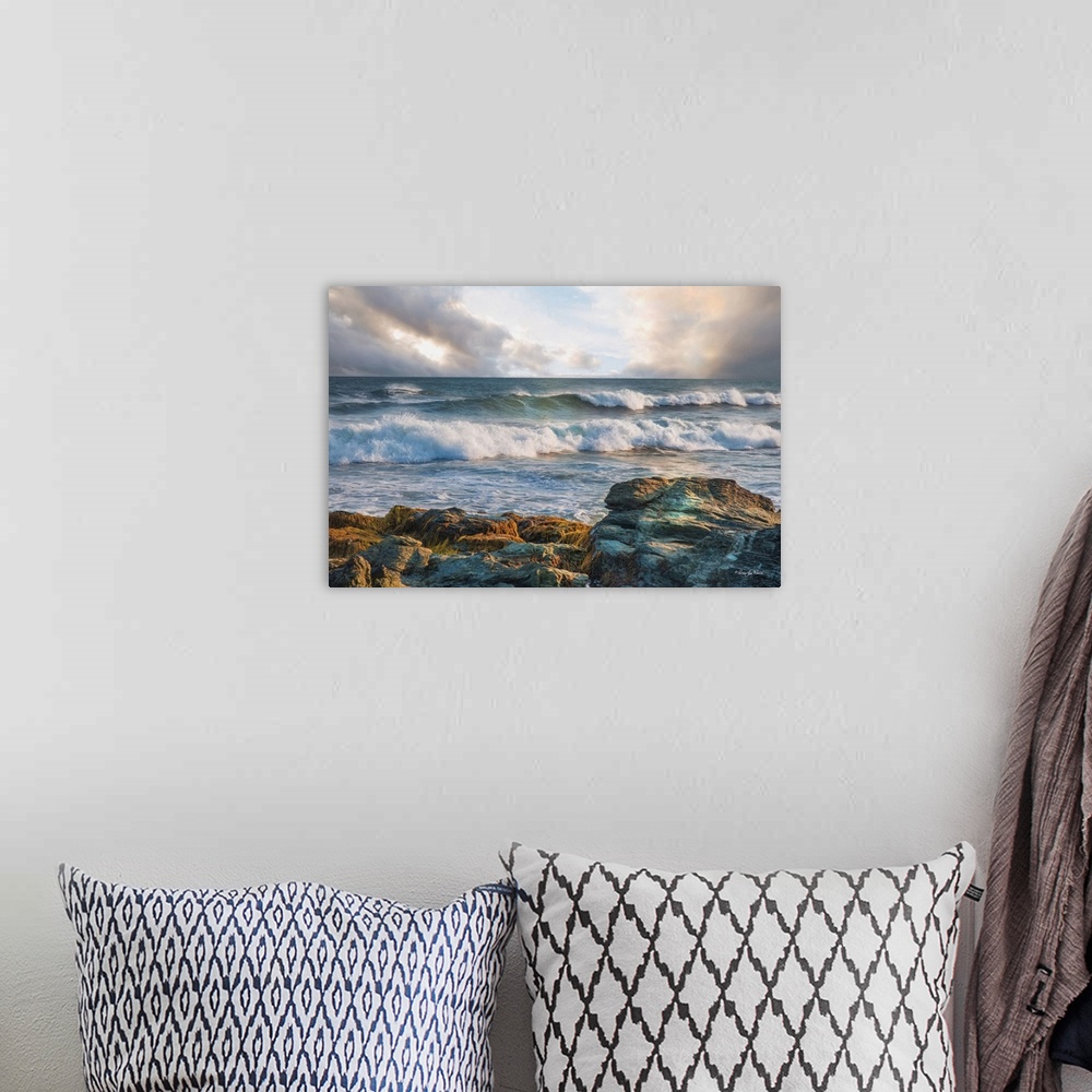 A bohemian room featuring Rolling waves in the ocean, seen from the rocky shore, with pastel clouds overhead.