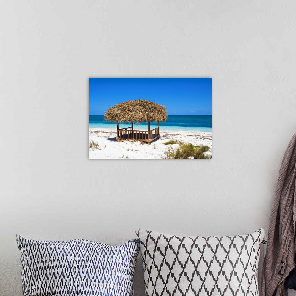 A bohemian room featuring Landscape photograph of a relaxing cabana on the white sands of a Cuban beach with crystal blue w...