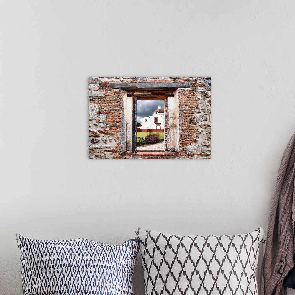 A bohemian room featuring View of a red and white church in Mexico framed through a stony, brick window. From the Viva Mexi...