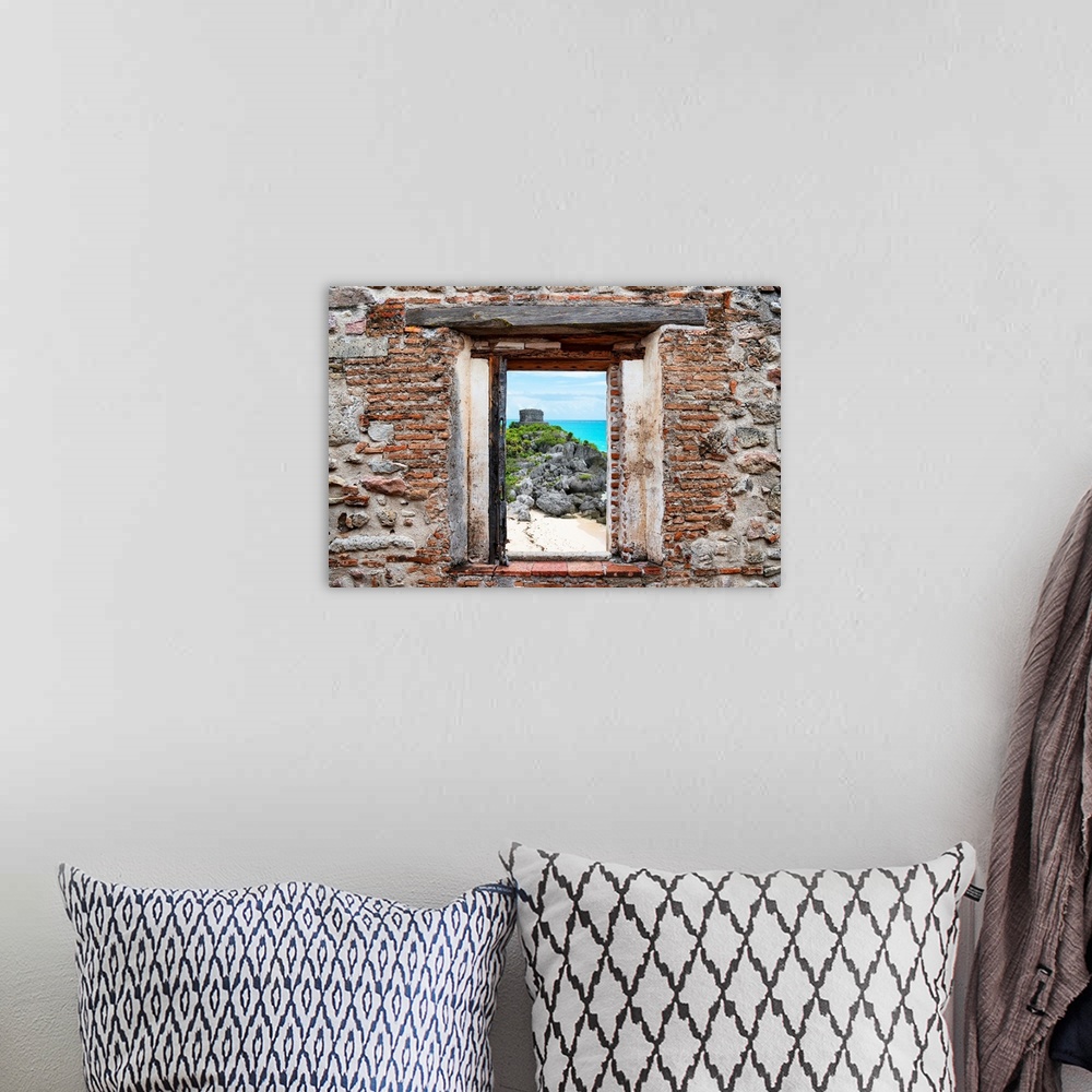 A bohemian room featuring View of the Tulum Ruins, Mexico, framed through a stony, brick window. From the Viva Mexico Windo...