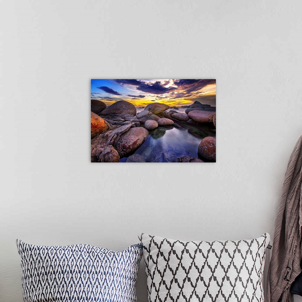 A bohemian room featuring Beautiful sunset colors and dramatic clouds over a rocky beach.