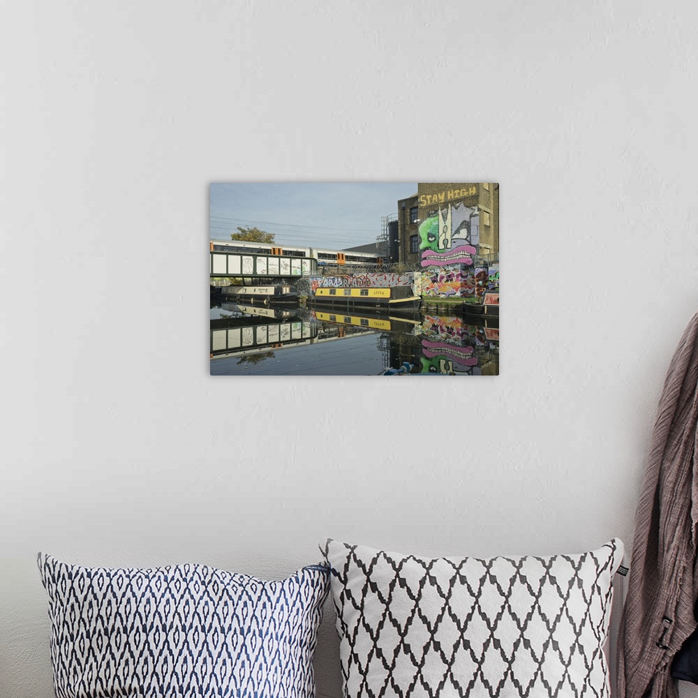 A bohemian room featuring Overground train drives past canal by artists studios and warehouses in Hackney Wick, London, Eng...