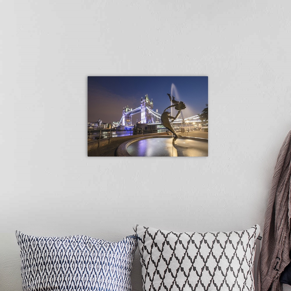 A bohemian room featuring The Girl With A Dolphin Fountain frames Tower Bridge reflected in the River Thames at night, Lond...