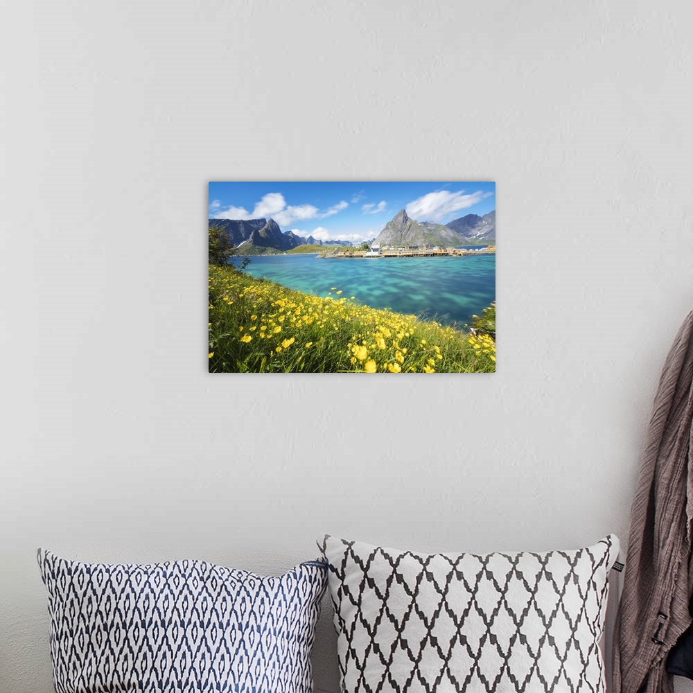 A bohemian room featuring Yellow flowers in bloom beside the turquoise sea and the fishing village of Sakrisoy, Reine, Mosk...