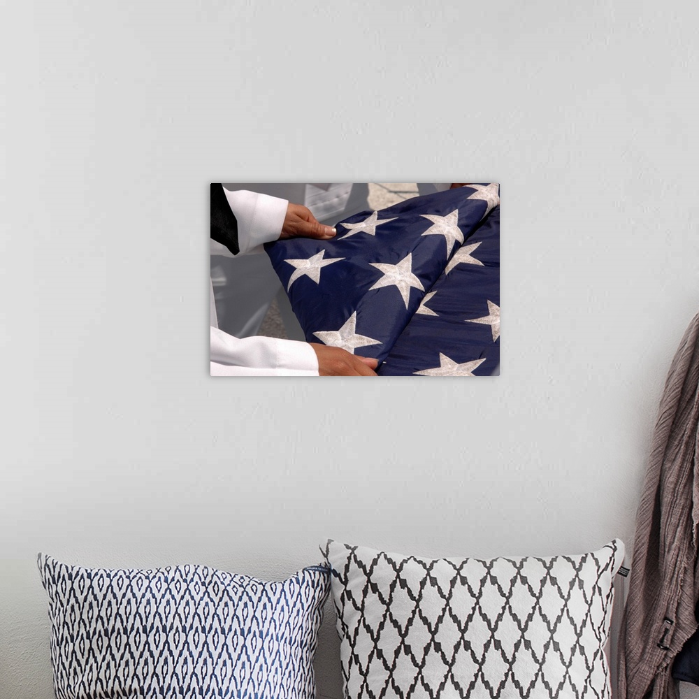 A bohemian room featuring Sailors assigned to the colors detail fold the national ensign.