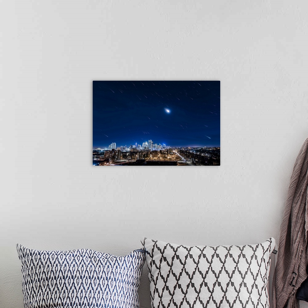 A bohemian room featuring Star trails of Orion, the moon, and the stars of winter over downtown Calgary, Canada.