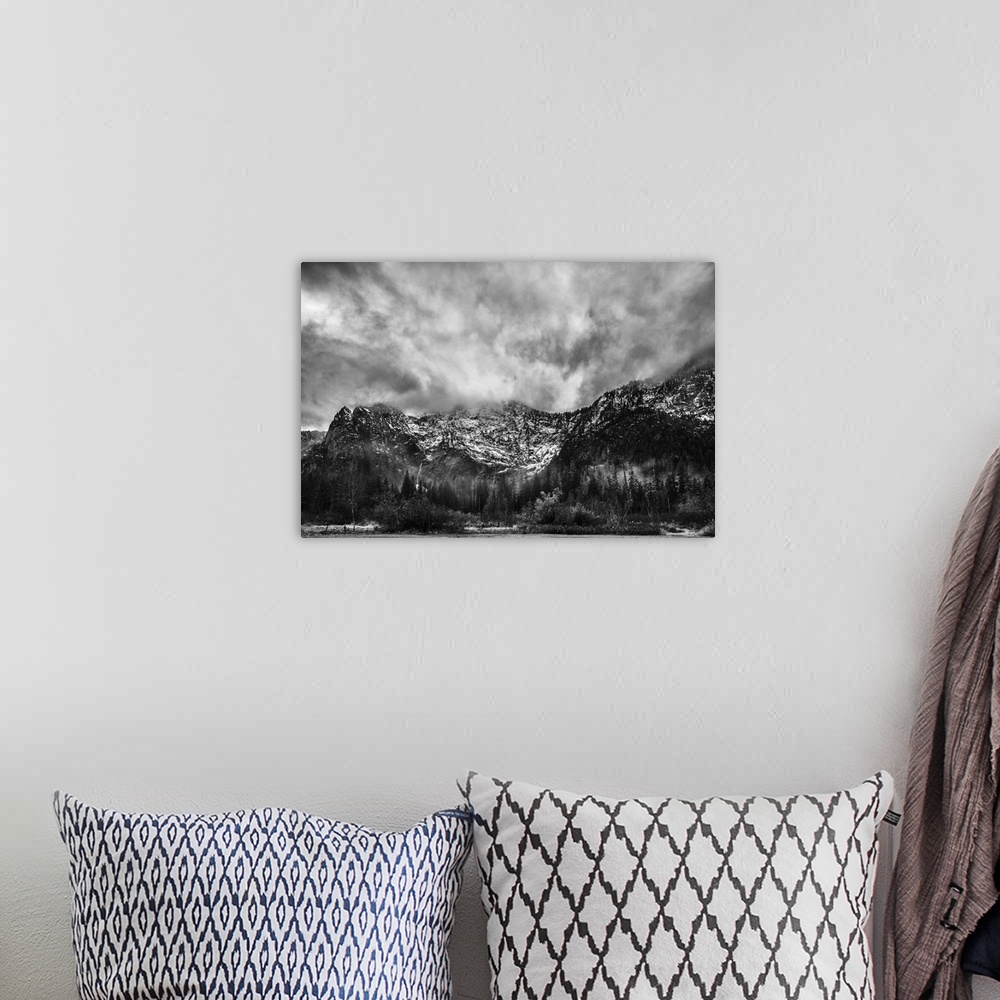A bohemian room featuring A black and white photograph of snow cover mountains and a heavy clouded sky.
