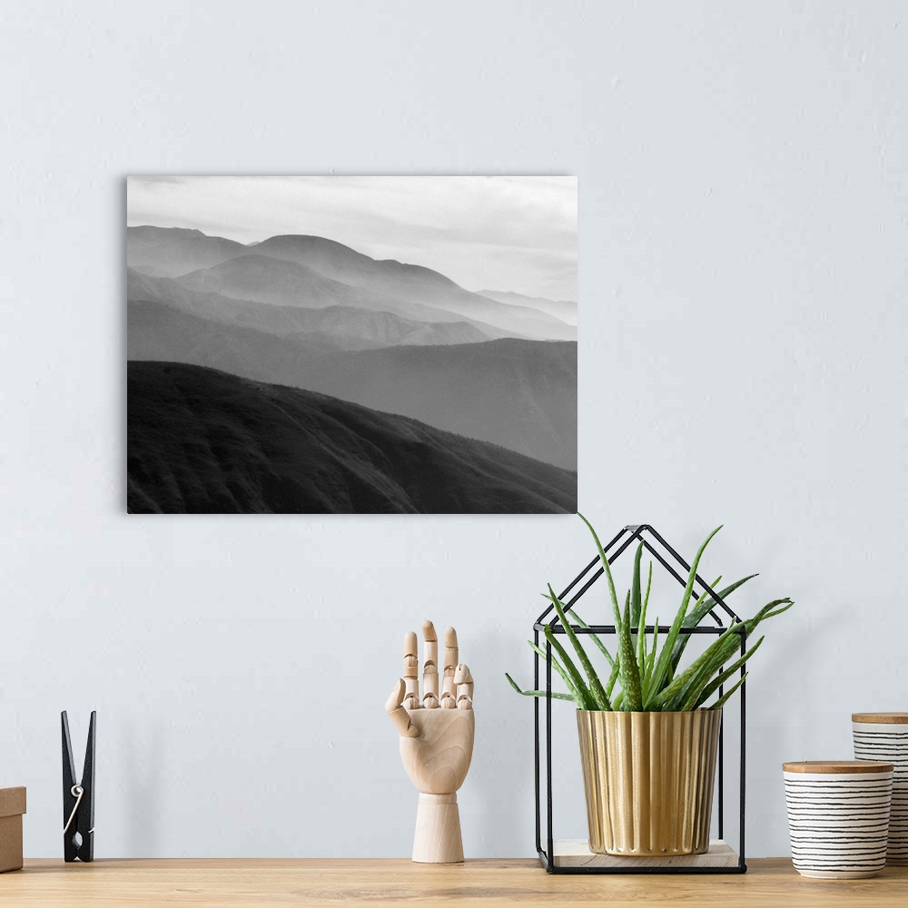 A bohemian room featuring A black and white photograph of a landscape of a silhouetted mountainous valley.