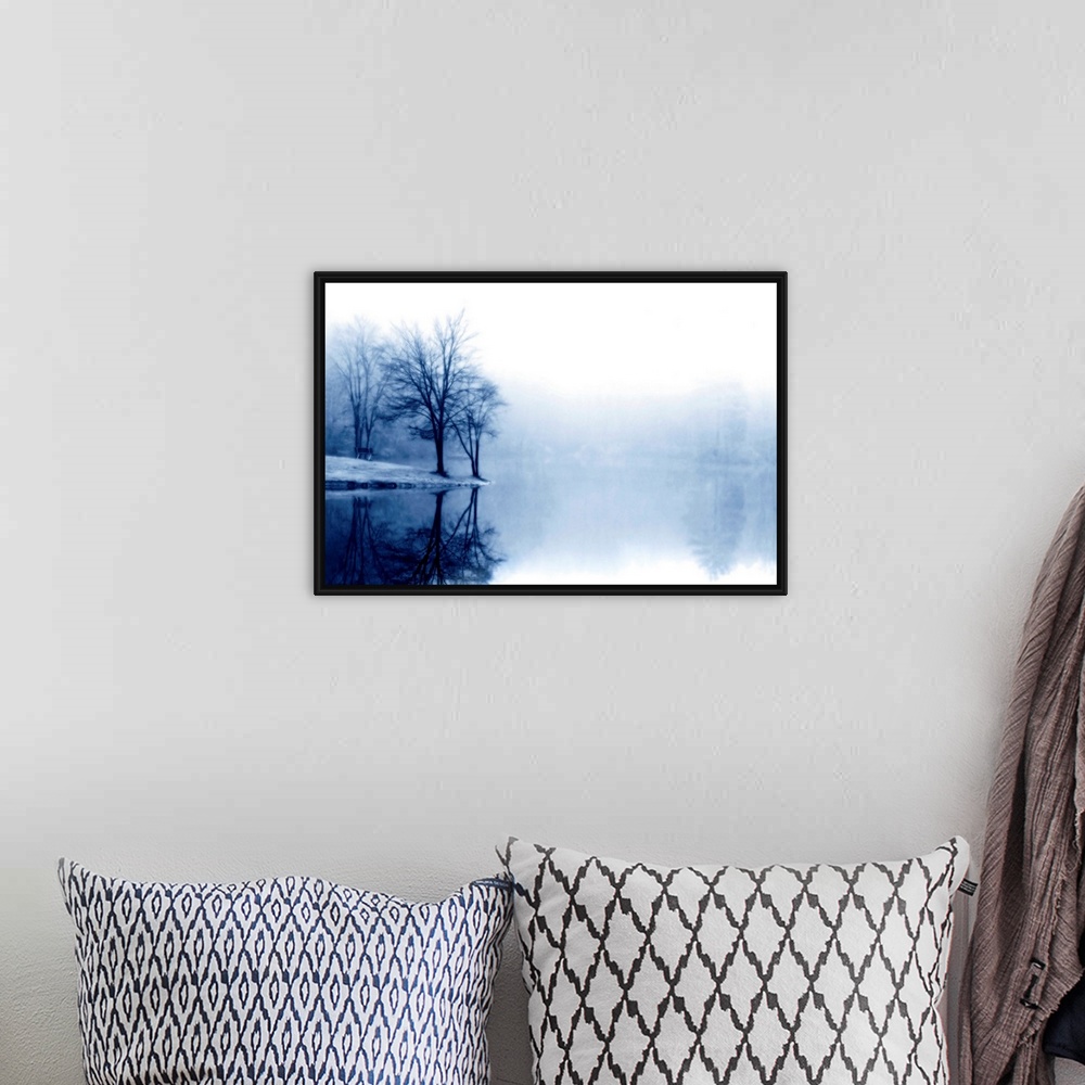A bohemian room featuring A photograph taken of a lake with bare trees off to the left side and more trees behind dense fog...