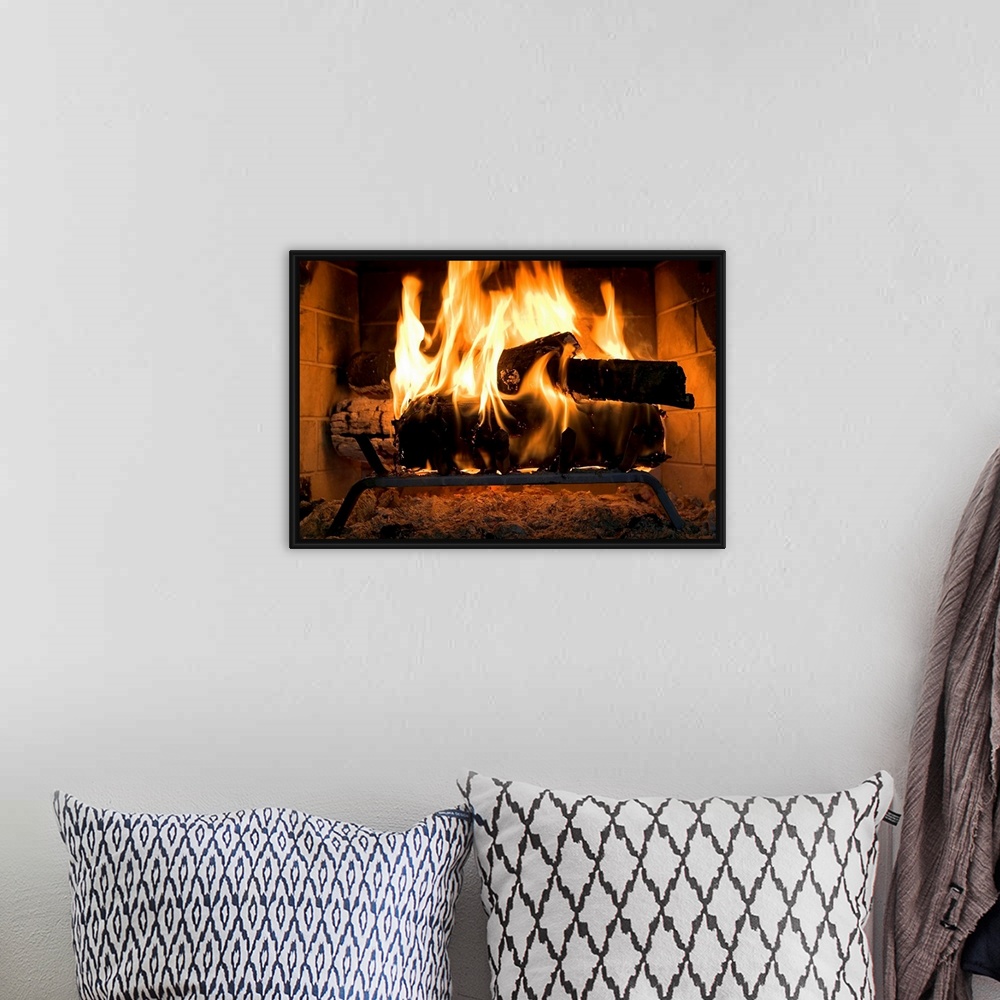 A bohemian room featuring A horizontal photograph of logs burning inside a personal, home fireplace lined with bricks