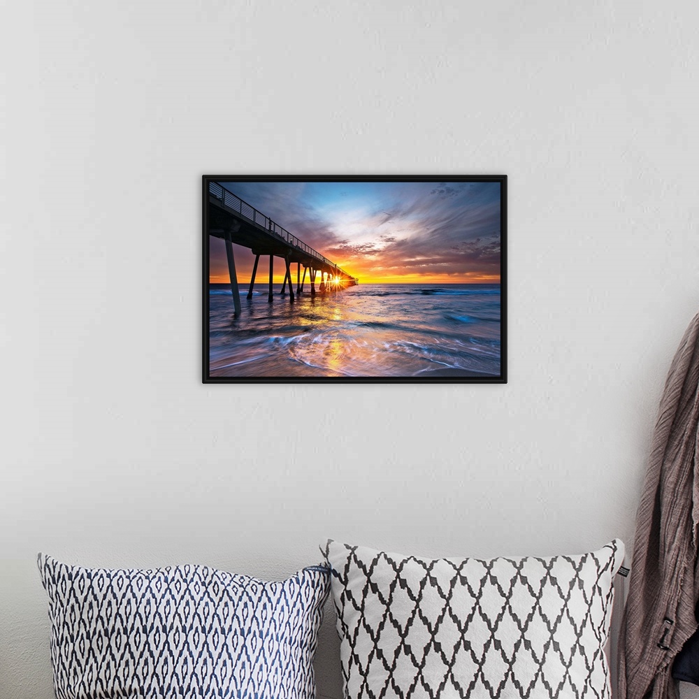 A bohemian room featuring Sun intersects pier at sunset with colorful waves and sky.