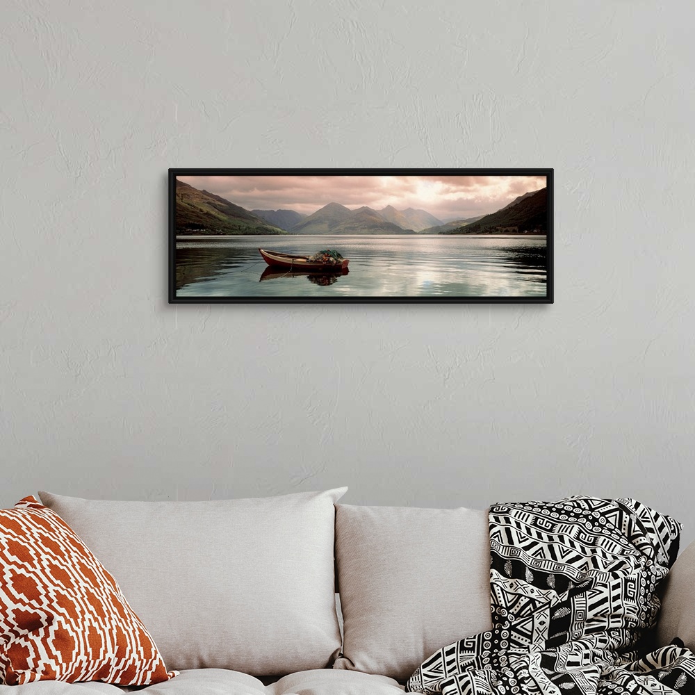 A bohemian room featuring Panoramic photograph shows a small fishing vessel sitting anchored within a calm body of water no...
