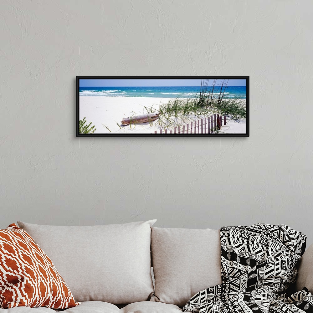 A bohemian room featuring Oversized landscape photograph of a fence running through grasses on the beach, in front of the r...