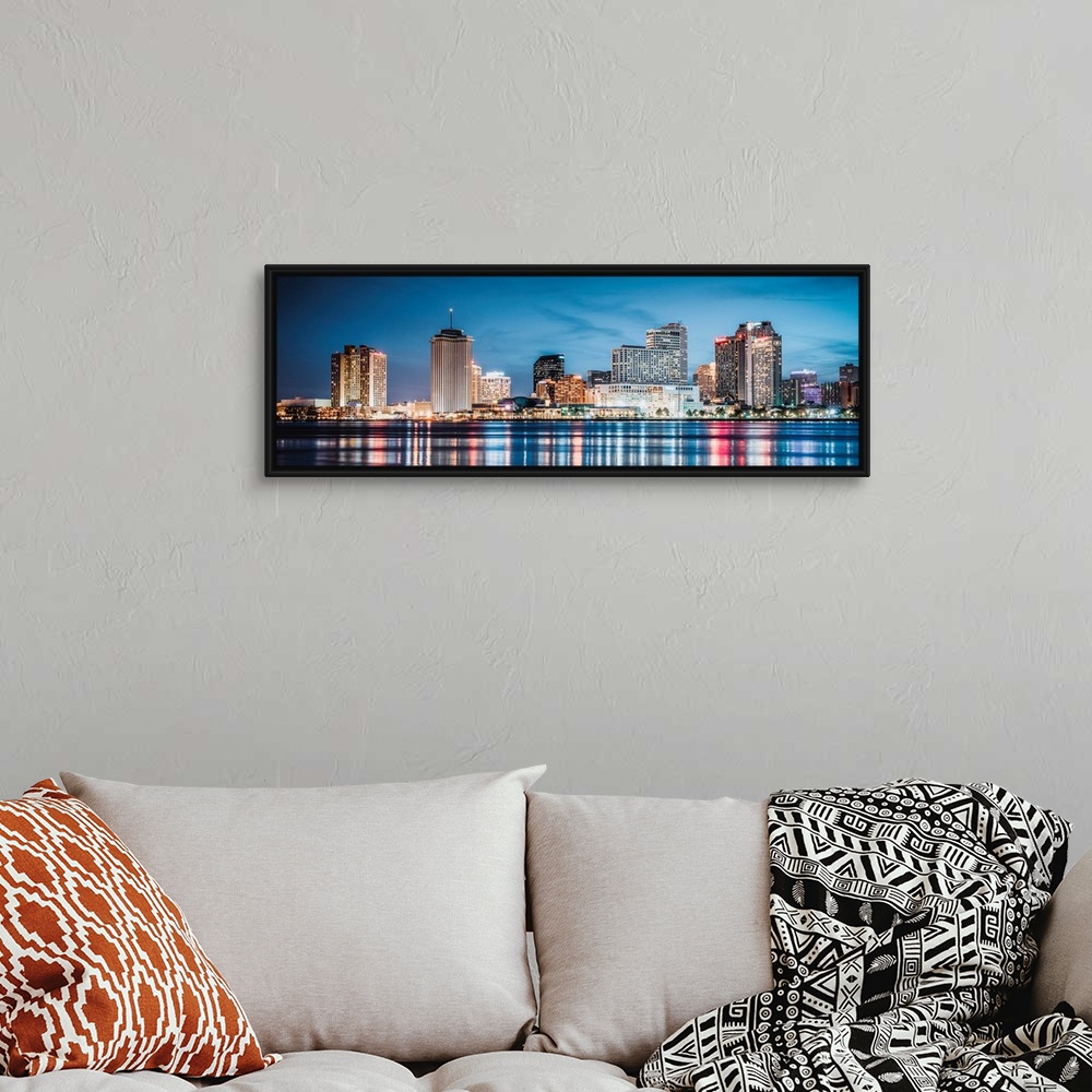A bohemian room featuring Panoramic photograph of the New Orleans skyline lit up at dusk and reflecting colorful bands onto...