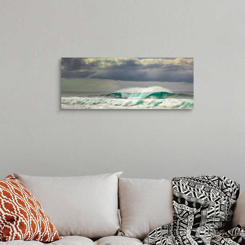A bohemian room featuring Panoramic image of crashing ocean waves with large clouds above.