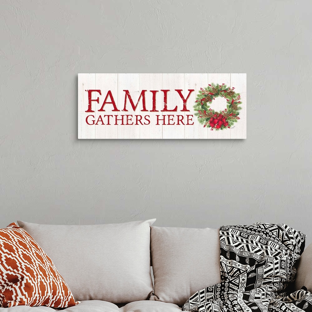 A bohemian room featuring "Family Gathers Here" in red with a holiday wreath on a white wood panel backdrop.