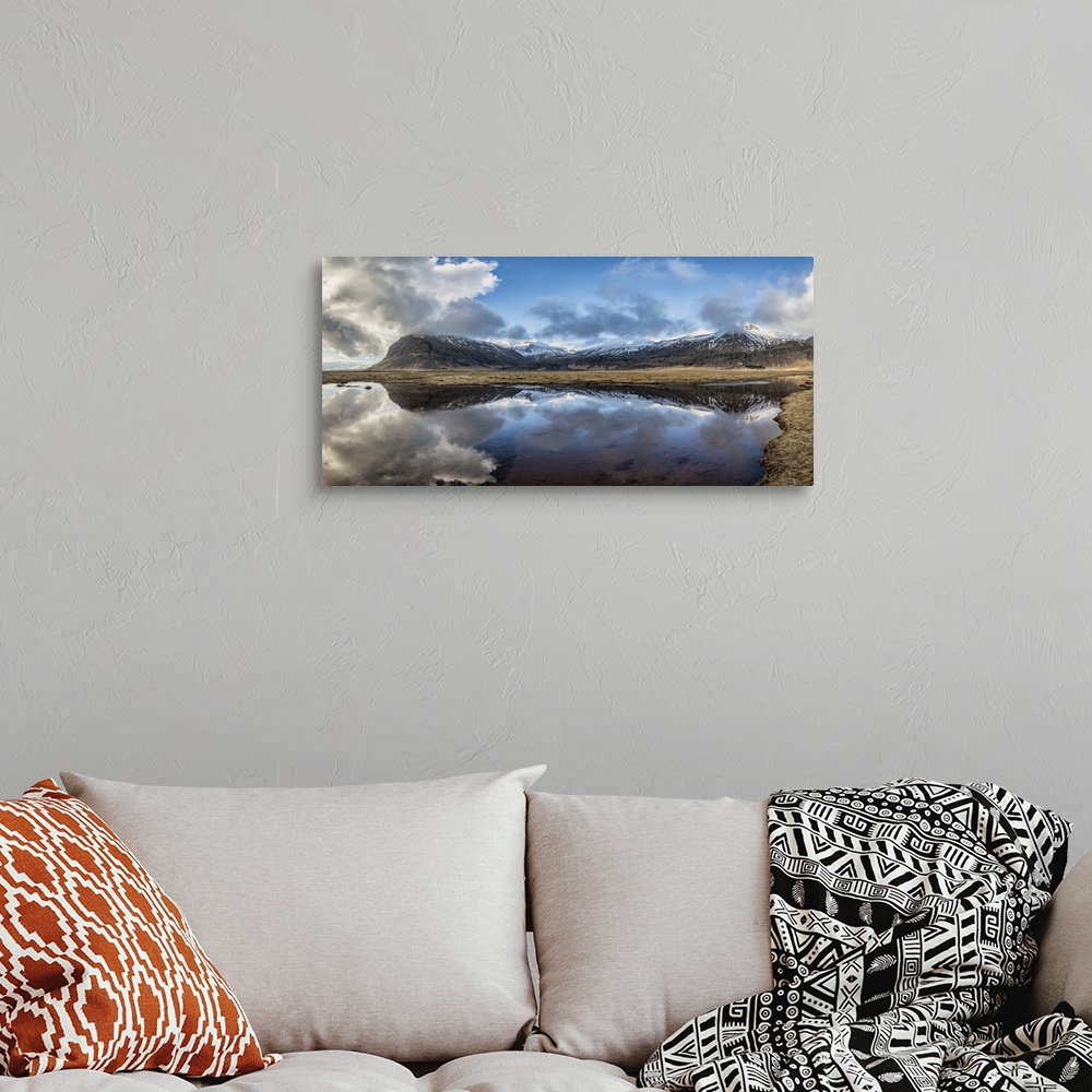 A bohemian room featuring Snow covered mountain panorama reflecting in a lake in Iceland.