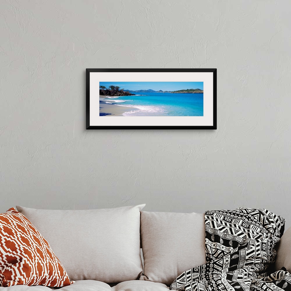 A bohemian room featuring Panoramic photograph displays the calm waters of this bay slowly crashing into the sandy beach, w...