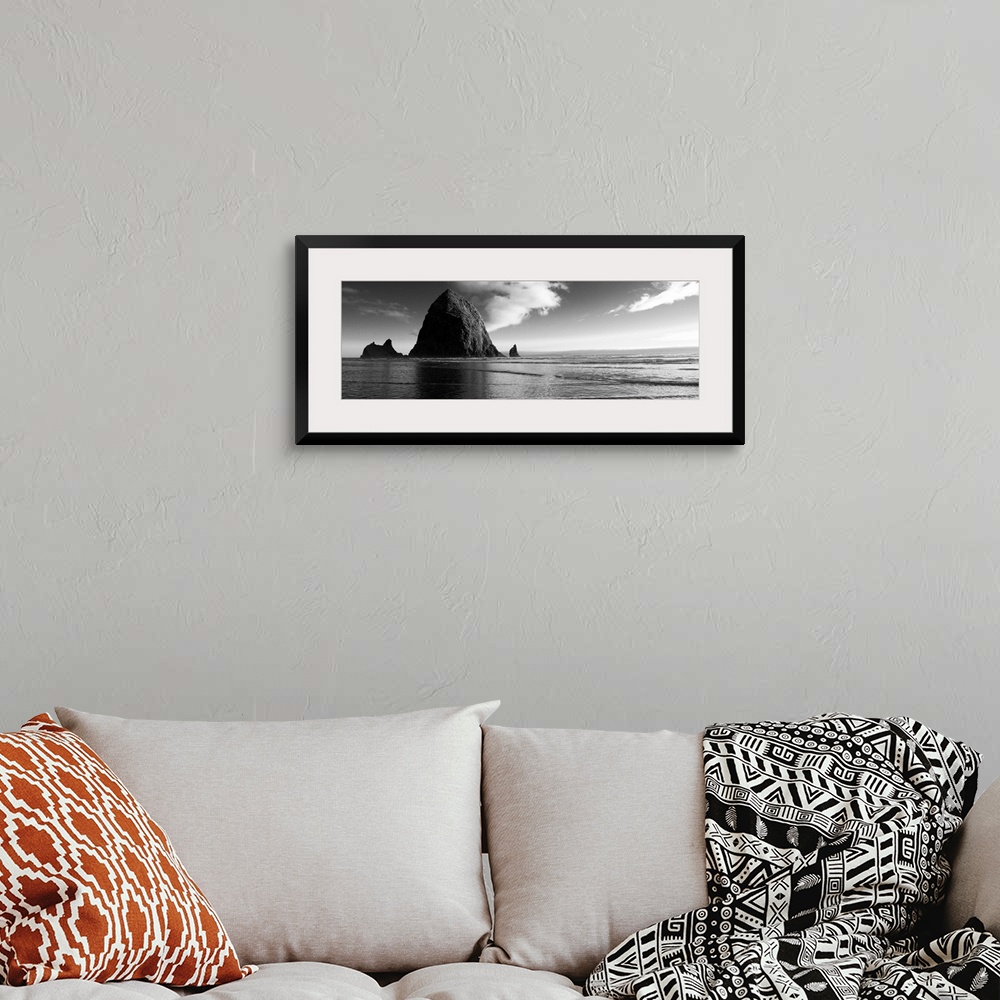 A bohemian room featuring Black and white panoramic photograph of Haystack Rock with rippling waters.