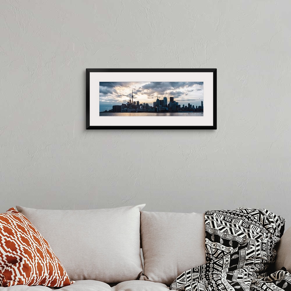 A bohemian room featuring Toronto city skyline under a dramatic sunset with clouds overhead, Ontario, Canada.