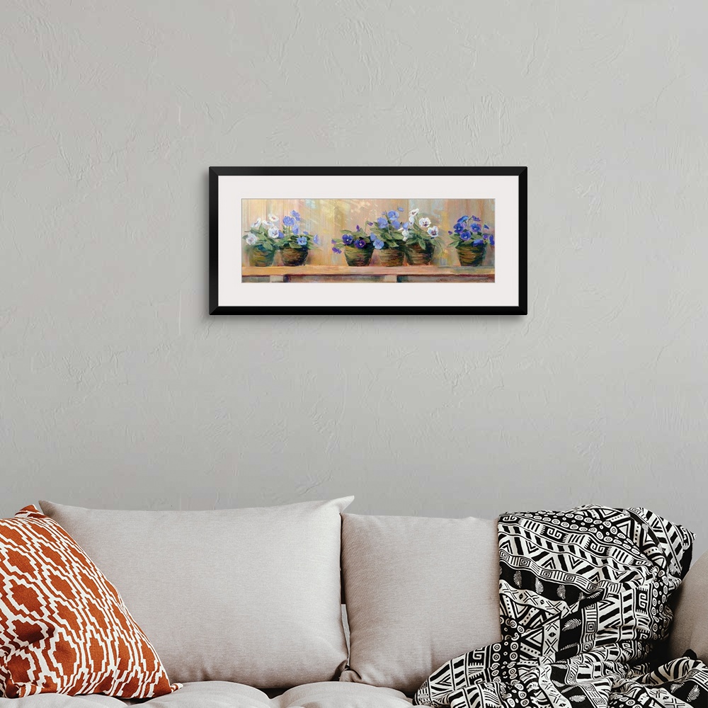A bohemian room featuring Panoramic floral art shows six potted flowers of varying color as they sit quietly on a shelf.