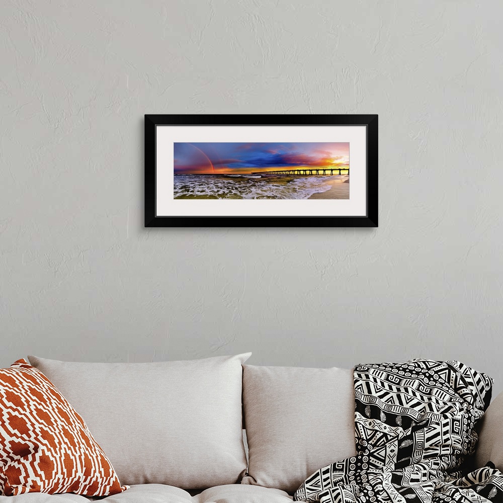 A bohemian room featuring A dark blue sky with a purple sunset featuring a full rainbow. A long pier can be seen reaching i...