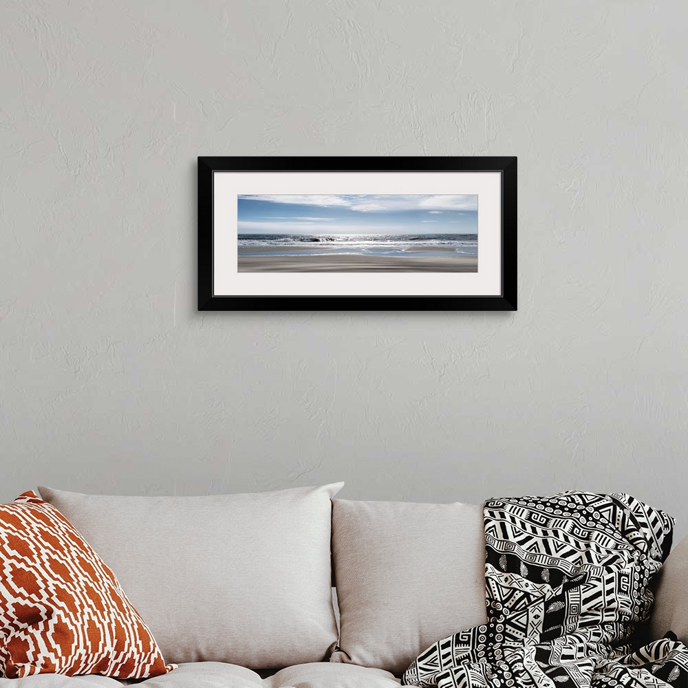 A bohemian room featuring A panoramic photo illustrating a tranquil view of the beach as the sun shimmers on the sea.