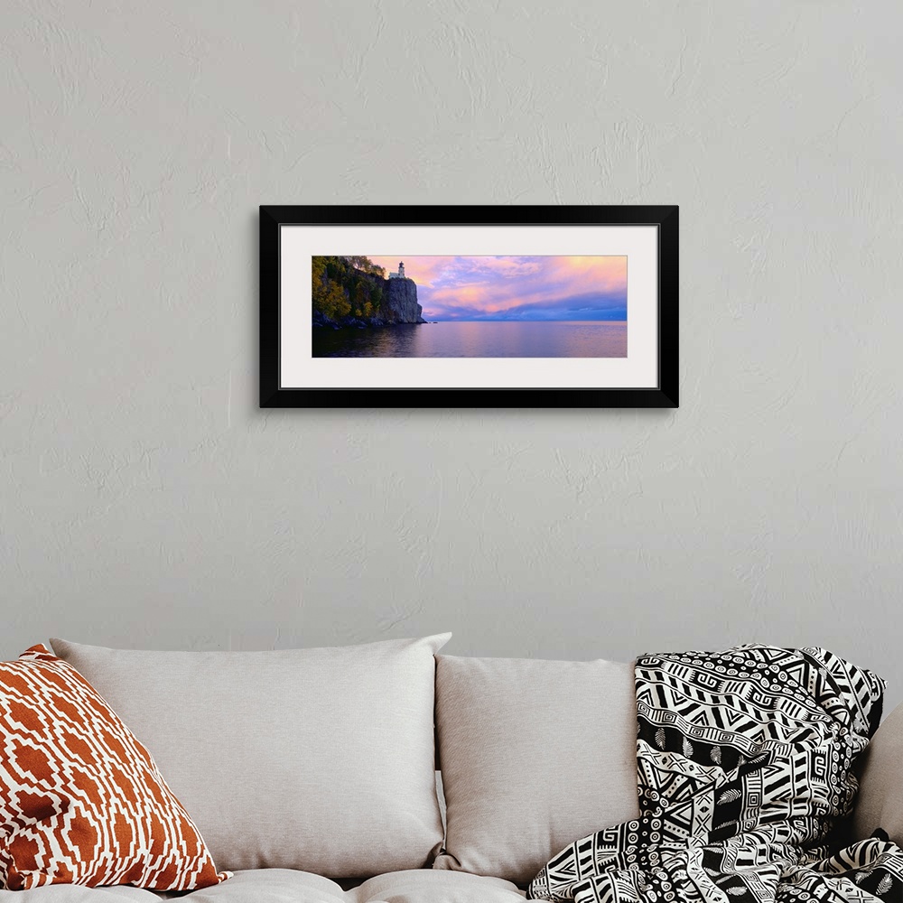 A bohemian room featuring Panoramic photo print of a lighthouse on top of a cliff overlooking the water at sunset.