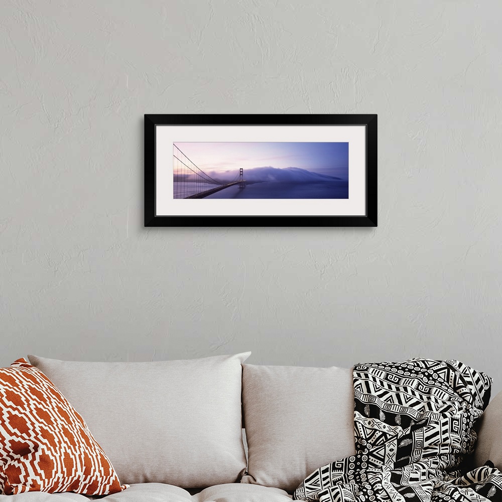 A bohemian room featuring Panoramic photograph of overpass crossing ocean and disappearing into fog.