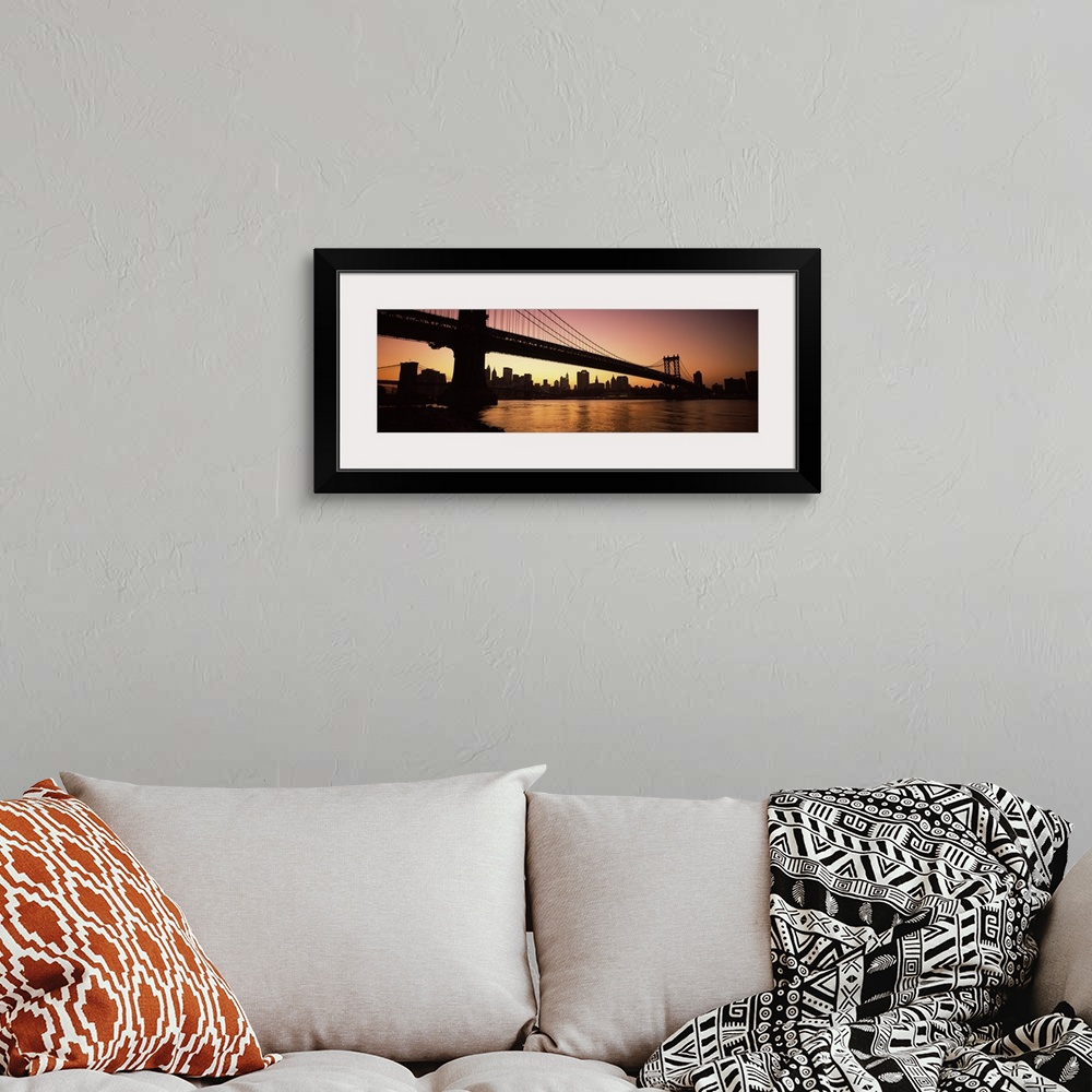A bohemian room featuring The Manhattan bridge and New York City skyline are silhouetted by the sunset.