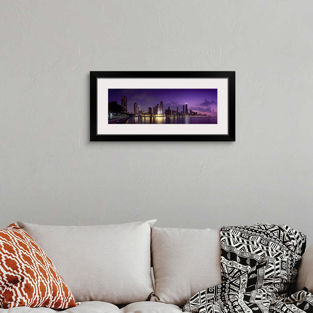 A bohemian room featuring Long canvas photo of a lit up cityscape at sunset by a waterfront.