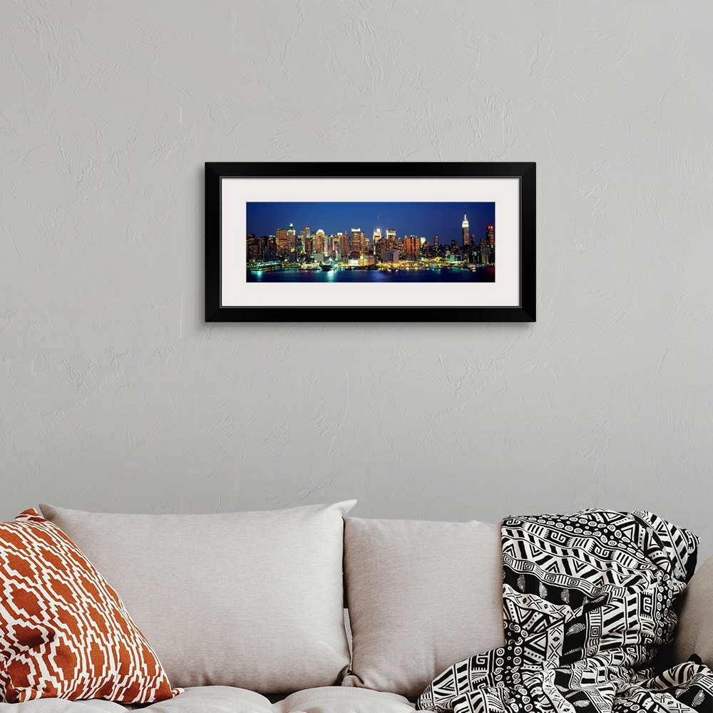 A bohemian room featuring A panoramic photograph of the Manhattan shore and skyscrapers illuminated at night.